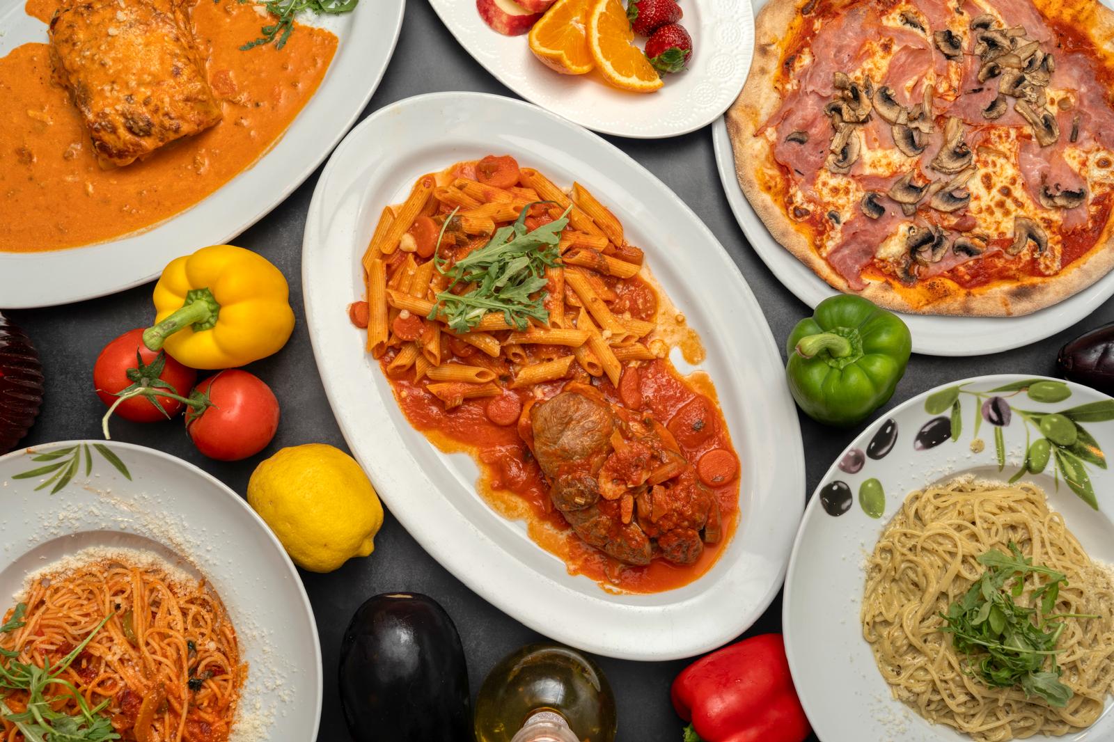 Une table de plats La Familia — pâtes, pizza et osso buco